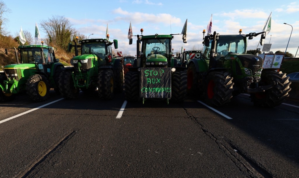 A banner handing on French farmer tractors reads ‘Stop to restrictions’ as they arrive near Chilly-Mazarin, south of Paris, on January 31, 2024 as French farmers maintain roadblocks on key highways into Paris for a third day, as part of nationwide protests called by several farmers’ unions over pay, tax and regulations. — AFP pic