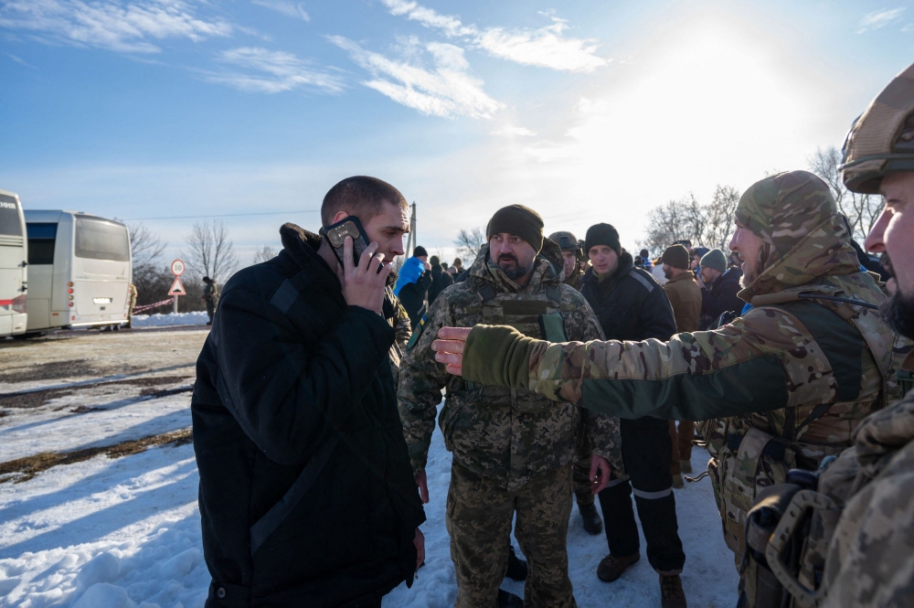 This file photograph taken and released by the Ukrainian presidential press service on January 31, 2024, showing a Ukrainian former prisoner of war speaking on the phone as he stands with servicemen following a prisoner exchange, amid Russia’s military invasion on Ukraine. — AFP pic