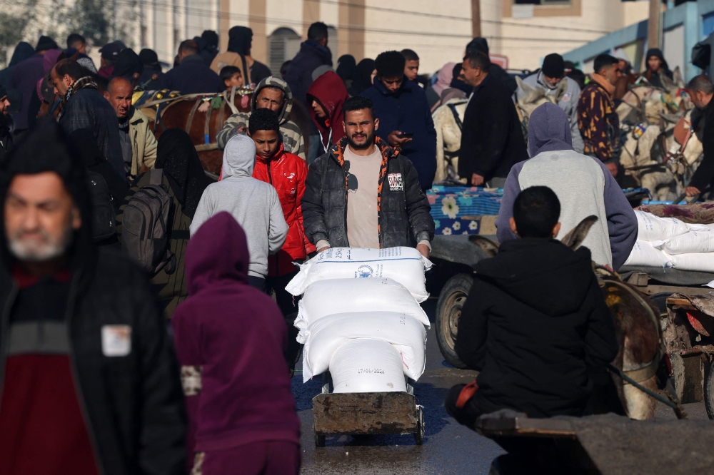 A man transports bags of flour distributed by a United Nations aid organisation in Rafah in the southern Gaza Strip on February 3, 2024, as fighting continues between Israel and the Palestinian Hamas group. — AFP pic