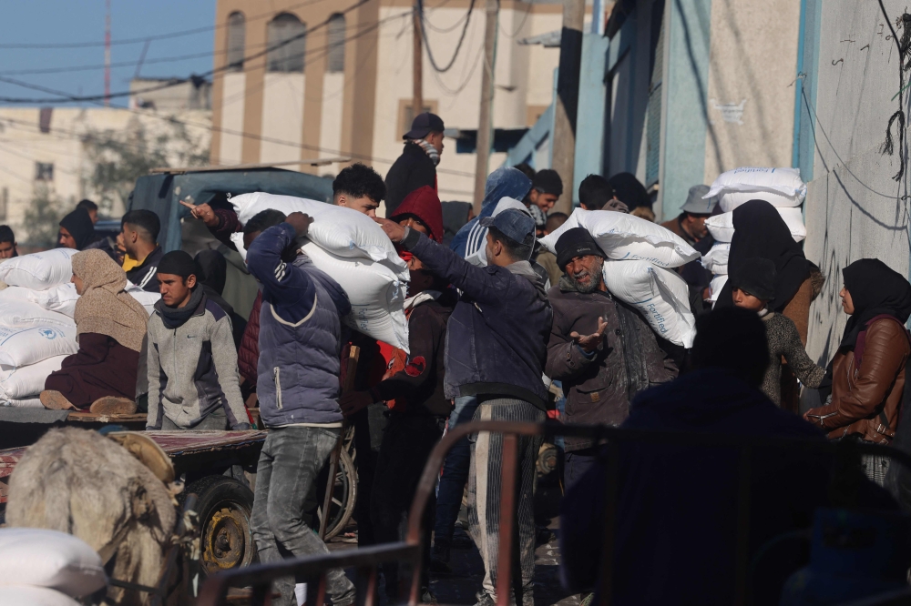 People receive bags of flour distributed by a United Nations aid organisation in Rafah in the southern Gaza Strip on February 3, 2024, as fighting continues between Israel and the Palestinian Hamas group. — AFP pic