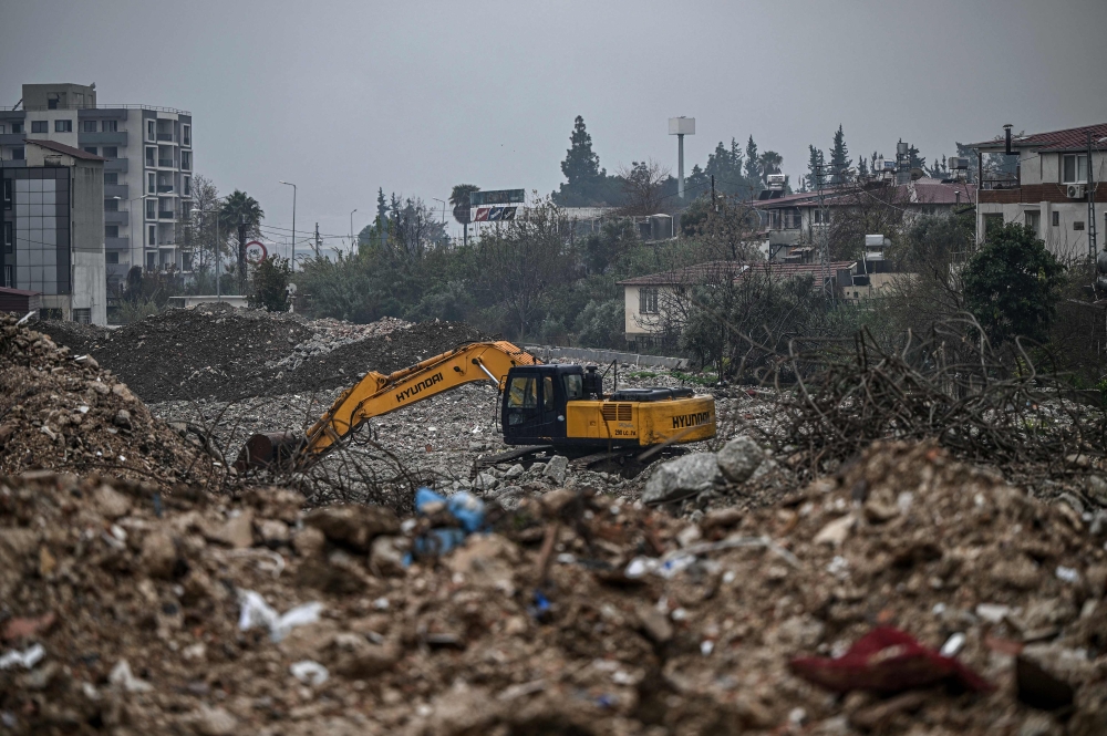 A digger works to clean the rubble of collapsed buildings, eleven months after a 7.8-magnitude jolt and its aftershocks wiped out swathes of Turkey’s mountainous southeast, in Antakya on January 12, 2024. — AFP pic