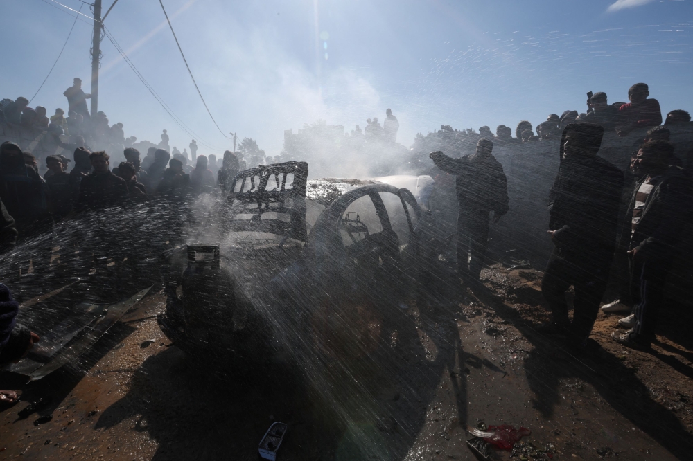 Palestinians gather around a car hit in an Israeli strike, amid the ongoing conflict between Israel and the Palestinian Islamist group Hamas, in Rafah in the southern Gaza Strip, February 4, 2024. — Reuters pic