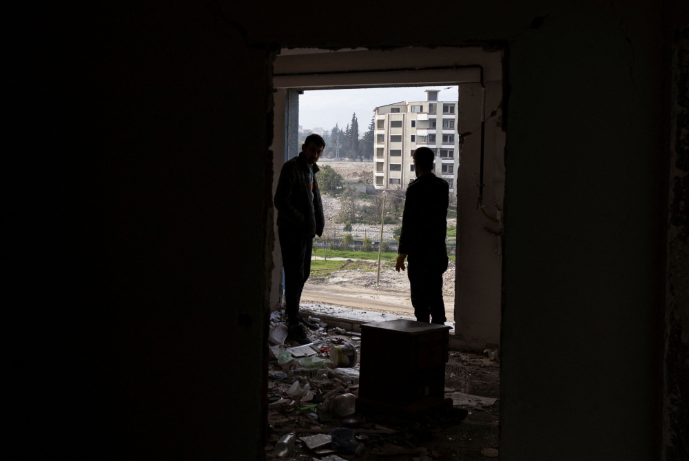 Ahmet Altinoz is accompanied by a friend as he watches the scene outside his lightly damaged apartment, which will be demolished soon, in the aftermath of last year's earthquake, in Hatay, Turkey, February 2, 2024. — Reuters pic