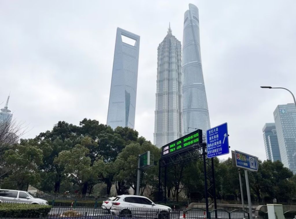 Cars travel past a display showing Shanghai and Shenzhen stock indexes near the Shanghai Tower and other skyscrapers at the Lujiazui financial district in Shanghai, China February 5, 2024. — Reuters pic