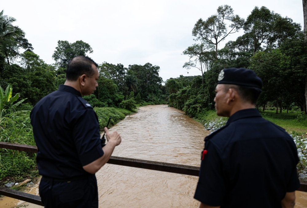 Tapah district police chief Supt Mohd Naim Asnawi (right) looks at the scene of the water surge incident at Sungai Kenjur at Kampung Poh, Bidor February 7, 2024. — Bernama pic