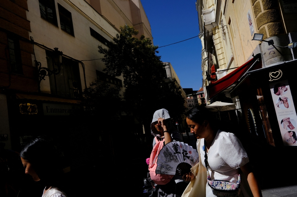 Tourists from China try to protect themselves from the sun and the high temperatures as Spain braces for the third heatwave of the summer in Madrid, Spain, August 7, 2023. — Reuters pic