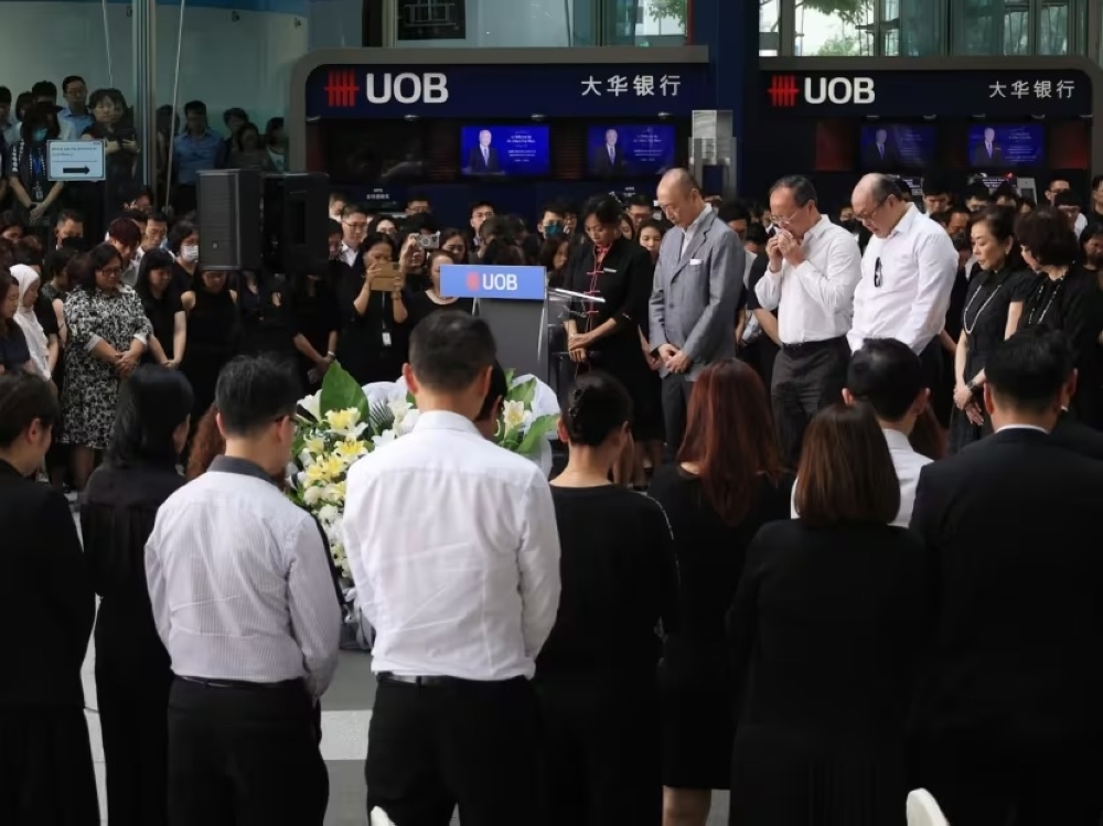 Wee Cho Yaw's family and United Overseas Bank employees observing a minute of silence during a memorial service held at UOB Plaza Atrium on Feb 7, 2024. — TODAY pic