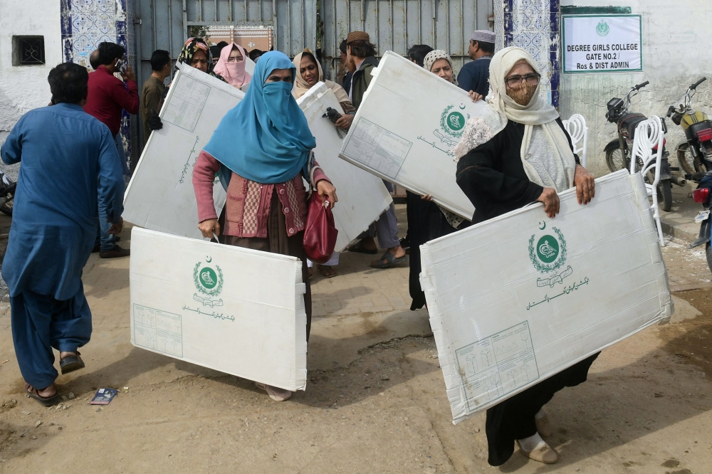 Election presiding officers leave after collecting voting materials at a distribution center in Karachi on February 7, 2024, a day prior Pakistan's national elections. — AFP pic