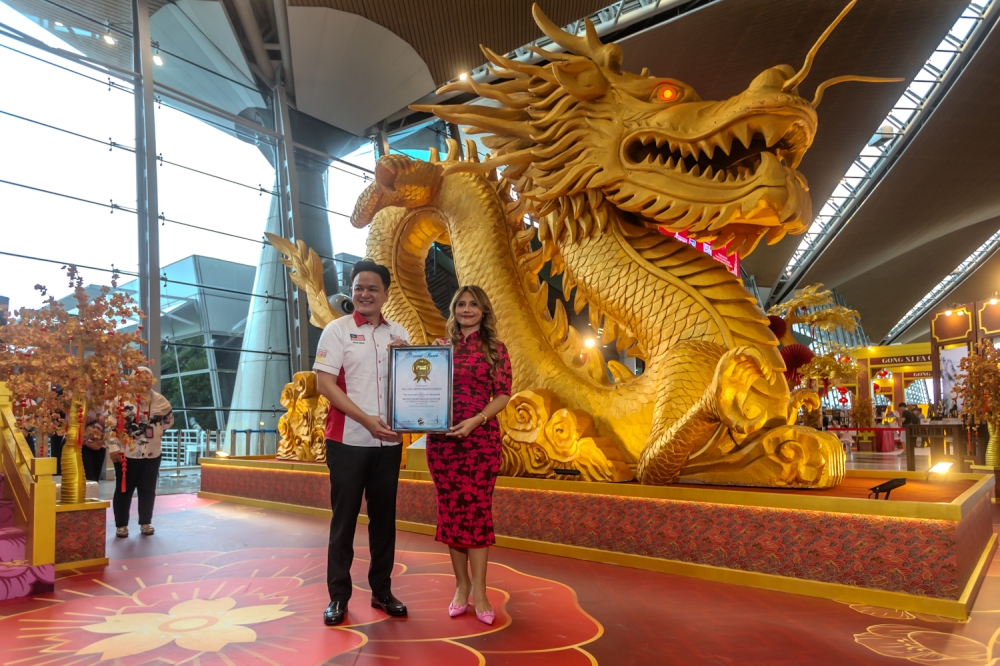 Malaysia Airports senior general manager and commercial services,Hani Ezra (right) being presented with the certificate for the record-breaking feat by Malaysia Book of Records's Chief Marketing Officer Jwan Heah Yeow Hooi (left). —Picture by Raymond Manuel. 