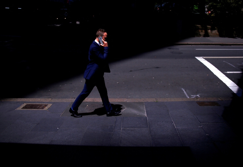 A businessman talks on his Apple iPhone as he walks along a street in the central business district (CBD) of Sydney October 24, 2017. — Reuters pic  