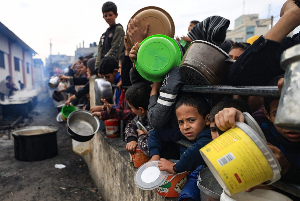 Palestinians children wait to collect food at a donation point in a refugee camp in Rafah. — AFP pic