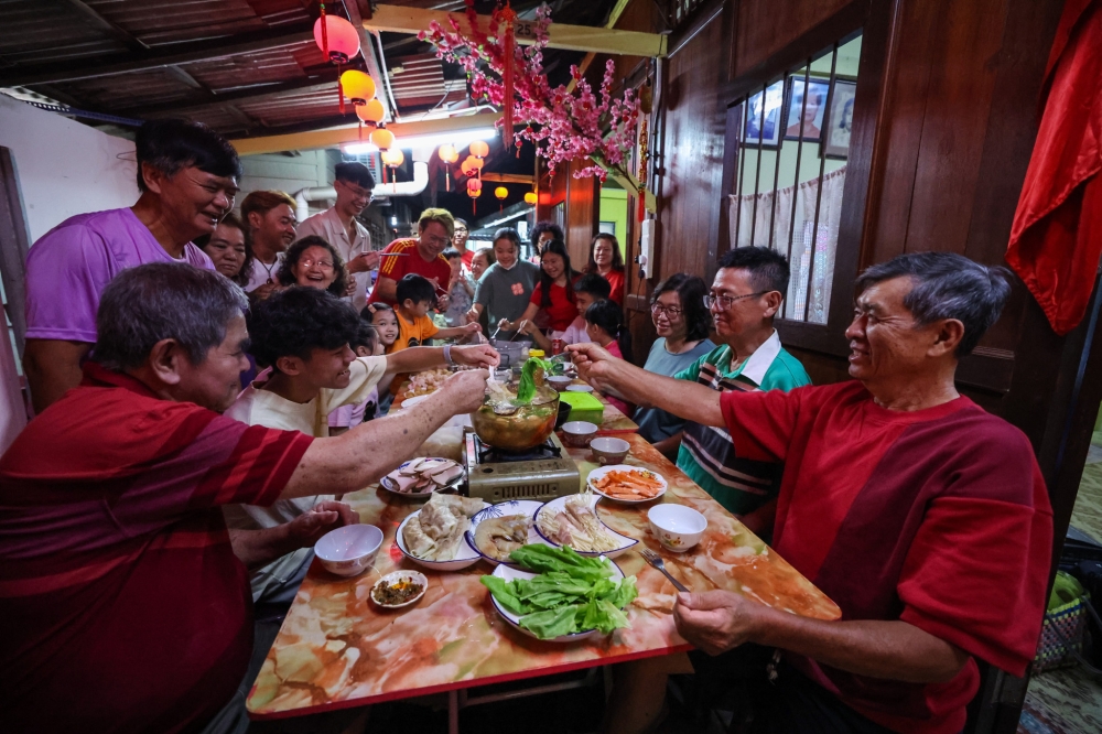Lim Chin Ewe, 69, (right) enjoying the reunion spread with his family at his home at Lim Jetty, Jalan Pengkalan Weld, February 9, 2024. — Bernama pic 