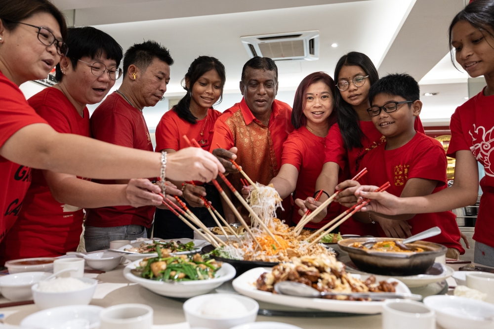 L Manimaran, 57, (centre) tosses Yee Sang with his wife Ooi Mei Kim, 50 (4th, right) and their family at a restaurant in Ipoh, February 9, 2024. — Bernama pic 