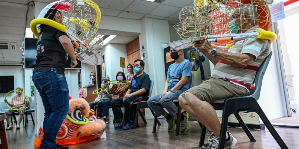 Lynn Wong (left, a martial artist who redesigned lion dance choreography for the seniors, demonstrating during a practice session for elderly residents in Singapore. — AFP pic