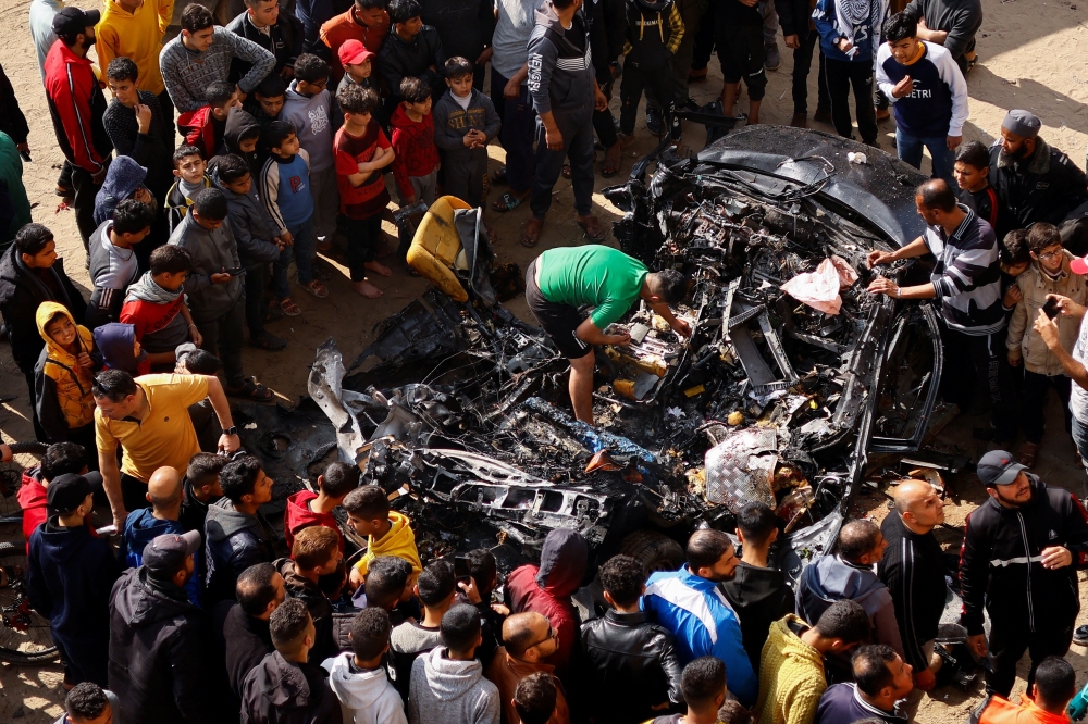 Palestinians inspect a car hit by an Israeli strike, amid the ongoing conflict between Israel and Palestinian group Hamas, in Rafah in the southern Gaza Strip, February 10, 2024. — Reuters pic
