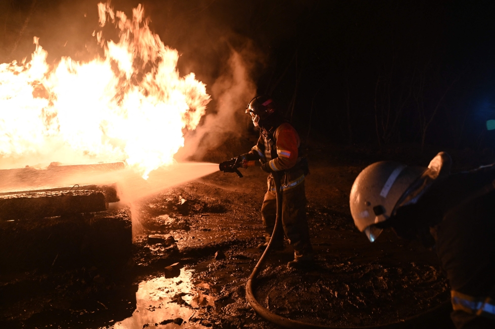 Ukrainian emergency personnel douse water to extinguish flames as they work at the site of a drone attack in Kharkiv, early on February 10, 2024. — AFP pic