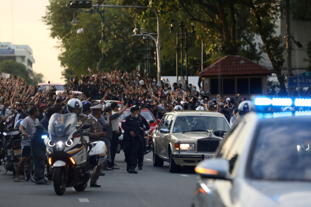 The royal motorcade carrying Thailand's Queen Suthida and Prince Dipangkorn drives past a group of anti-government demonstrators in front of Government House, on the 47th anniversary of the 1973 student uprising, in Bangkok, Thailand October 14, 2020. — Reuters pic