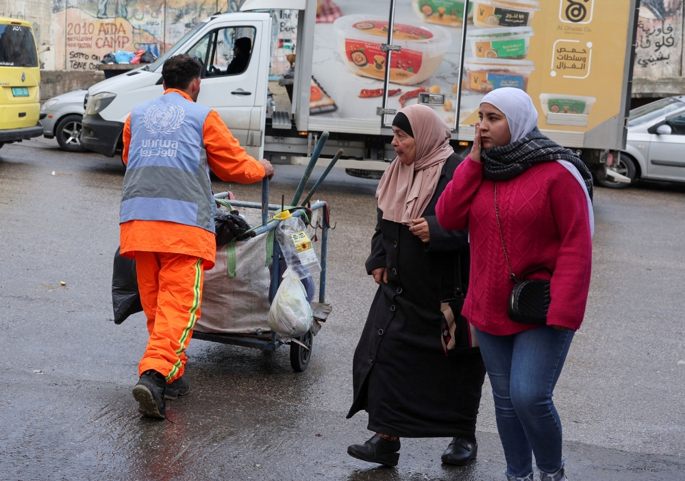 Palestinians walk past a UNRWA worker in the Aida refugee camp in Bethlehem in the Israeli-occupied West Bank, February 5, 2024. — Reuters pic