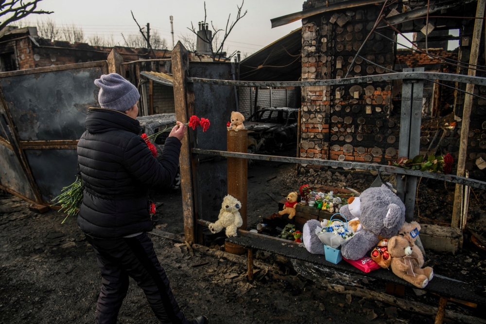 A woman lays flowers as she commemorates a family of two adults and three children, local residents who were killed on Friday, February 9, at their house that burned in a Russian drone strike, amid Russia's attack on Ukraine, in Kharkiv, Ukraine February 12, 2024. ― Reuters pic 