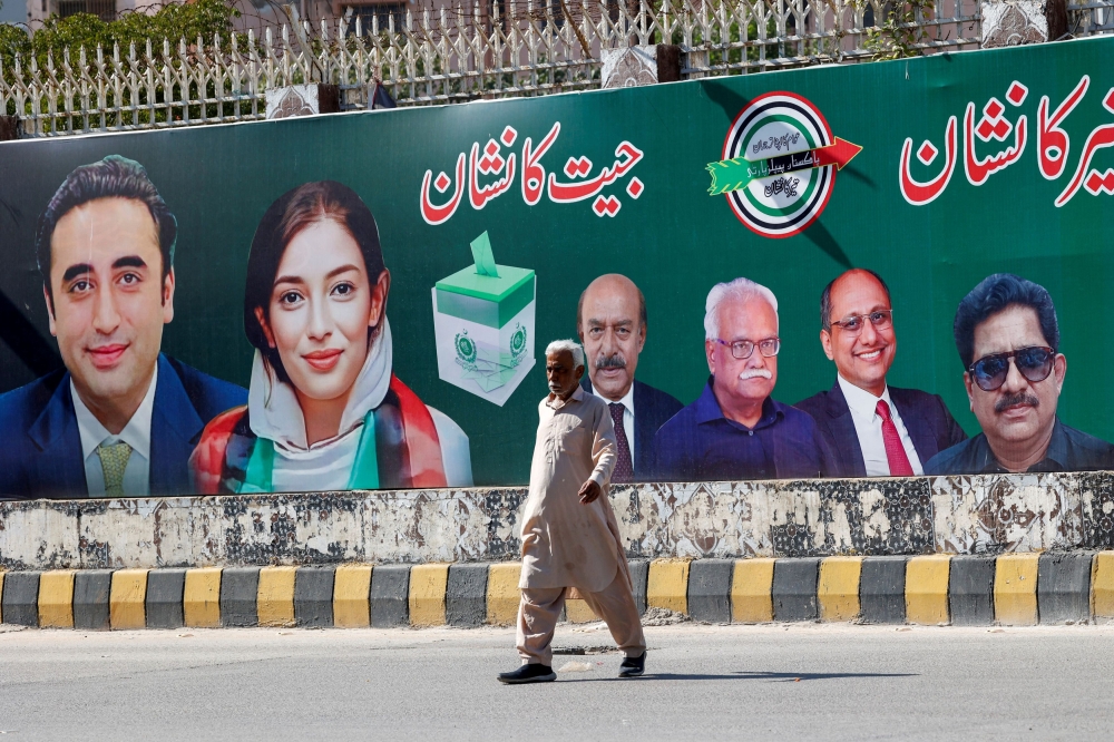 A man walks next to a billboard displaying photos of politician Bilawal Bhutto and his sister Asifa Bhutto, a day after general elections in Karachi, Pakistan February 9, 2024. — Reuters pic