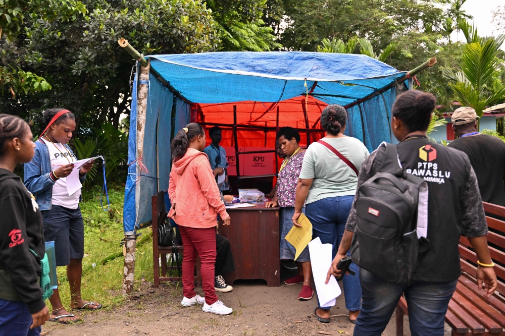 People register to cast their ballots and vote in Indonesia's presidential and legislative elections at a polling station in Kwamki Narama district, Mimika regency, Central Papua on February 14, 2024. — AFP pic