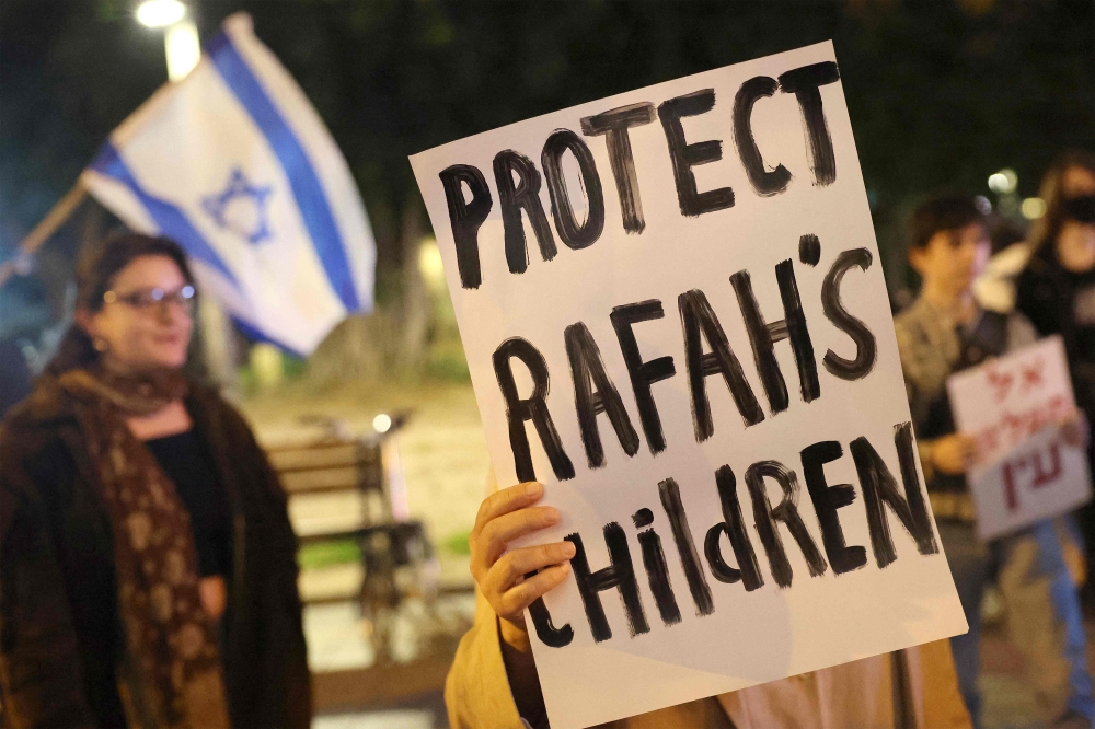 Demonstrators gather with signs during a protest by Israeli left-wing activists against the war in the Gaza Strip and the planned ground operation in Rafah, outside the Kirya military base which houses the Defence Ministry in Tel Aviv on February 13, 2024 amid the ongoing conflict in Gaza between Israel and the Palestinian militant group. — AFP pic