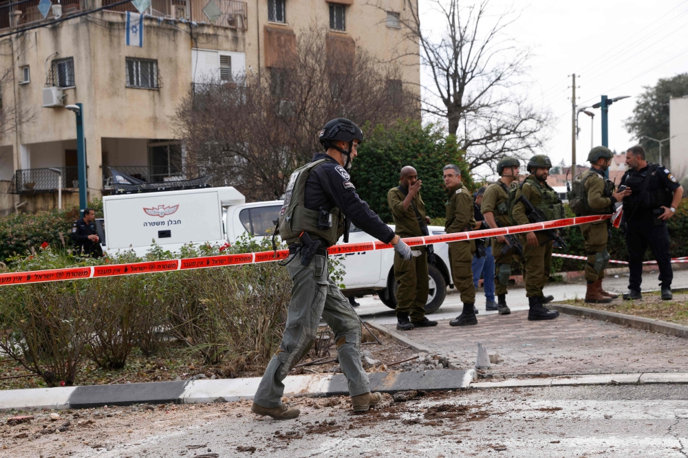 Israeli security forces inspect the area hit by rockets fired from soutern Lebanon in the northern Israeli border town of Kiryat Shmona on February 13, 2024. — AFP pic