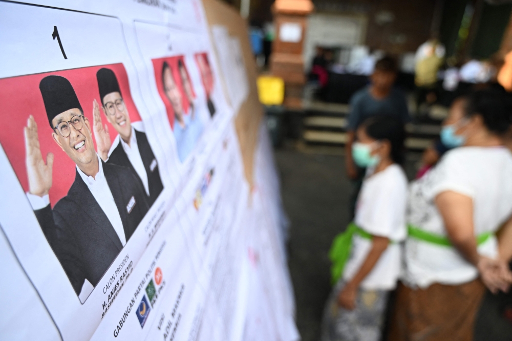 Lists of candidates in Indonesia's presidential and vice presidential elections, including presidential candidate Anies Baswedan (L) and vice presidential candidate Muhaimin Iskandar, are displayed during Indonesia's presidential and legislative elections at a polling station in Banjar Teba, Jimbaran on the resort island of Bali on February 14, 2024. — AFP pic