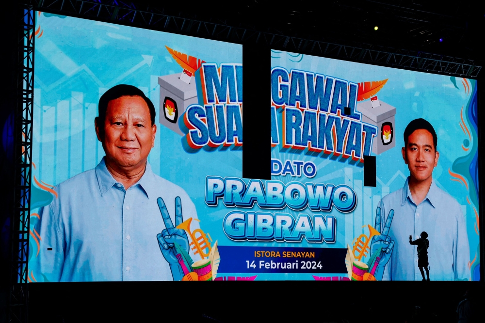 A worker checks a large screen showing Presidential candidate Prabowo Subianto and Vice President candidate Gibran Rakabuming Raka, the eldest son of outgoing President Joko Widodo before the start of an event where counting results will be displayed in Jakarta, Indonesia, February 14, 2024. — Reuters pic