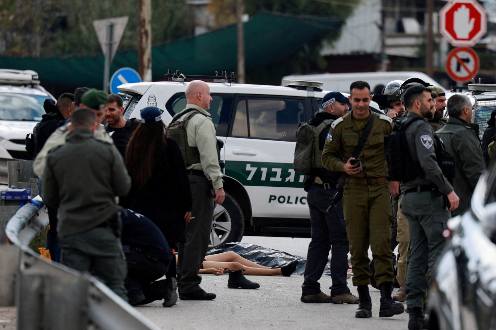 The body of a Palestinian man lies on the road as Israeli security forces secure the area of a suspected stabbing attack, near Maale Adumim settlement in the Israeli-occupied West Bank, February 5, 2024. — Reuters pic