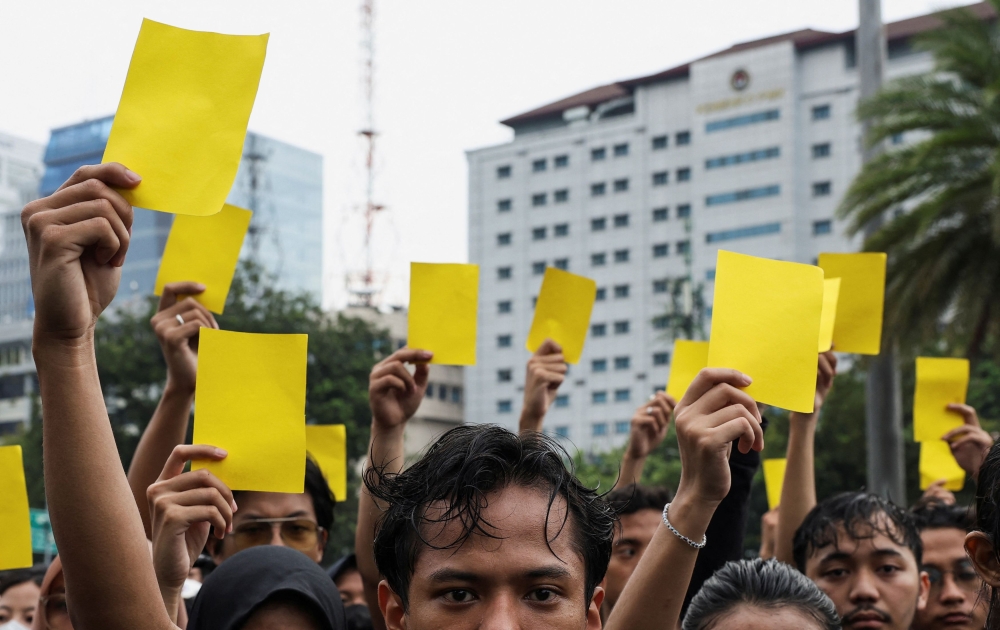 People raise yellow papers during a silent protest called 