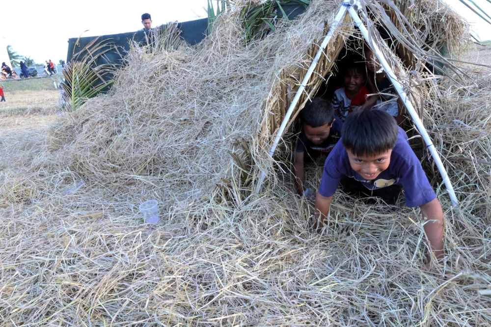 A group of cheerful children play ‘Straw Fort’ at the Straw and Wau Festival in Kampung Benua. — Bernama pic 