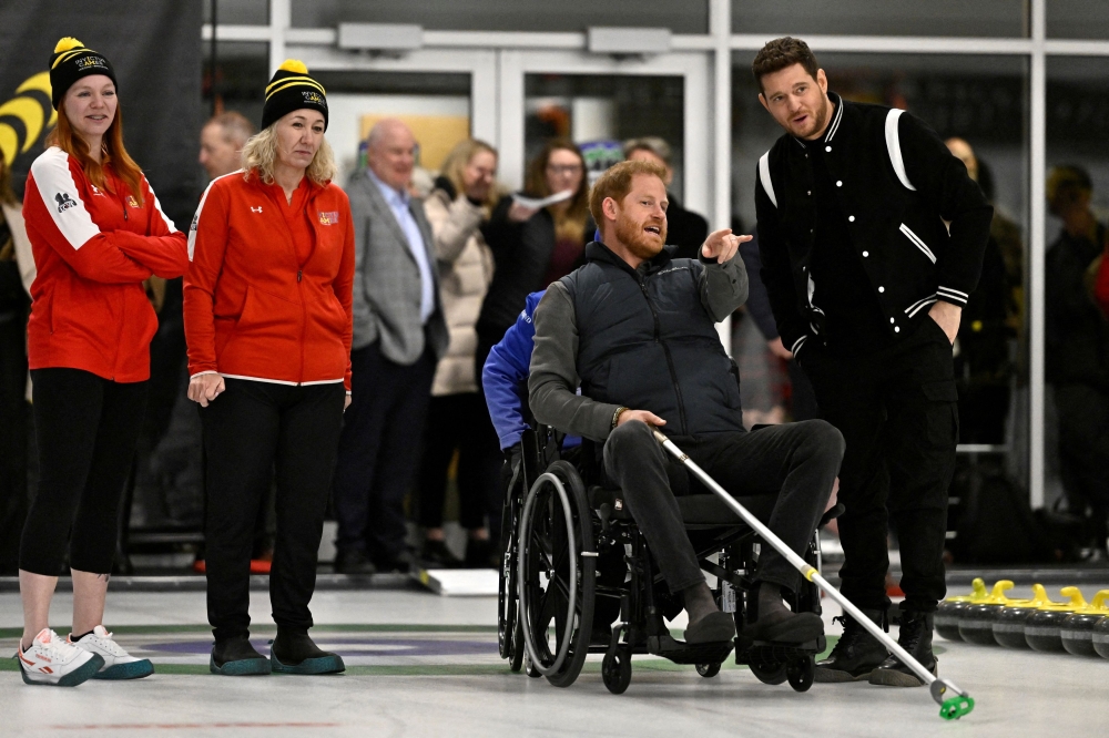 Britain's Prince Harry, Duke of Sussex, along with Michael Buble attempts wheelchair curling at the Hillcrest Community Centre during a visit to the training camp for the Invictus Games Vancouver Whistler 2025 in Vancouver, British Columbia February 16, 2024. — Reuters pic