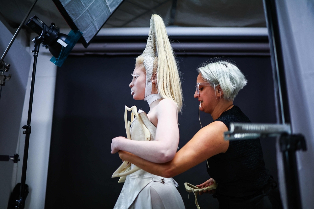 Costume designer Syban Velardi-laufer helps Albino and non-binary model Nan M, represented by Zebedee talent agency, get dressed with one of her creations before a photoshoot, in a studio in east London, on February 11, 2024. — AFP pic 