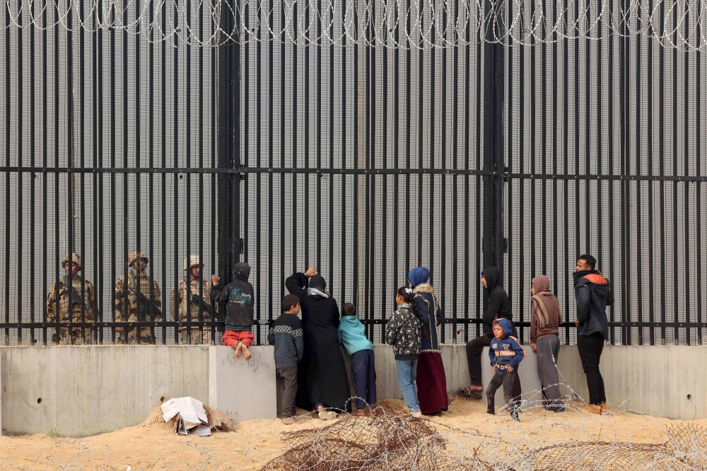 Displaced Palestinians talk to Egyptian soldiers at the border fence between Gaza and Egypt, on February 16, 2024 in Rafah, in the southern Gaza Strip, amid the ongoing conflict between Israel and the Palestinian Hamas group. ― AFP pic