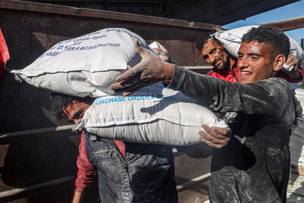Workers unload bags of humanitarian aid that entered Gaza by truck through the Kerem Shalom (Karm Abu Salem) border crossing in the southern part of the Palestinian territory on February 17, 2024, in Rafah on the southern Gaza Strip, amid the ongoing conflict between Israel and Hamas. ― AFP pic