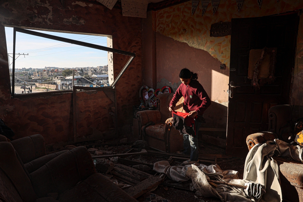 A Palestinian girl collects salvageable items in a building damaged during the Israeli bombardment of Rafah. — AFP pic