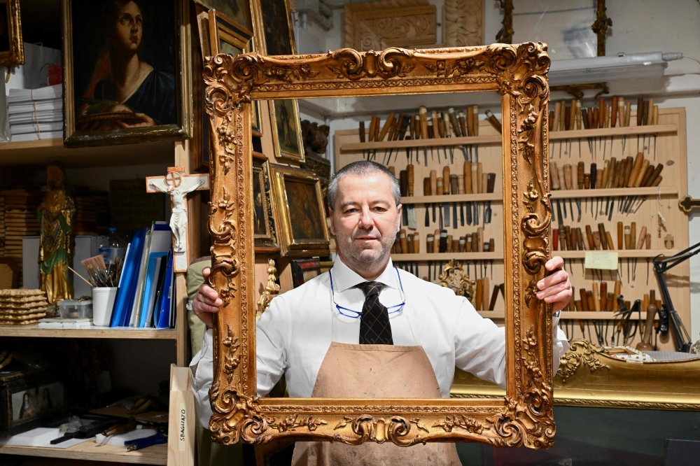 Gabriele Maselli president of Florence's Historical Businesses Association, poses in his workshop where he paints gold picture frames by hand, in Florence, on February 15, 2024. — AFP pic