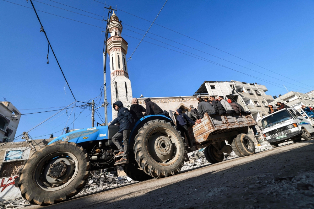 People ride in a cart pulled by a tractor past the rubble of a destroyed building and a mosque minaret in Rafah in the southern Gaza Strip on February 14, 2024. — AFP pic
