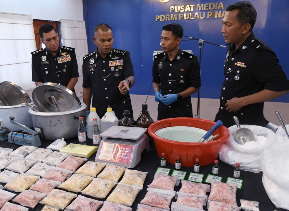 Penang deputy police chief Datuk Mohamed Usof Jan Mohamad (2nd left) looks at the various drugs and equipment seized in the raid during a press conference in George Town, February 19, 2024. — Bernama pic   