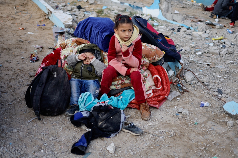 Children rest outside after they were evacuated from Nasser Hospital. — Reuters pic