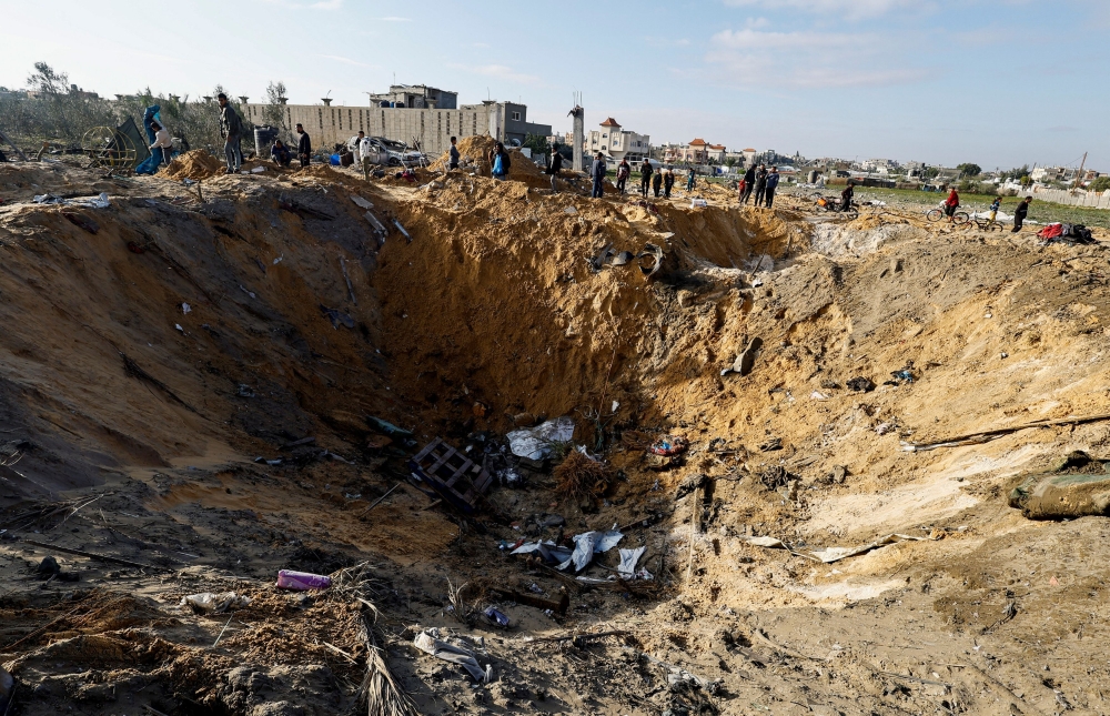 Palestinians gather near a crater at the site of an Israeli strike in Rafah. — Reuters pic