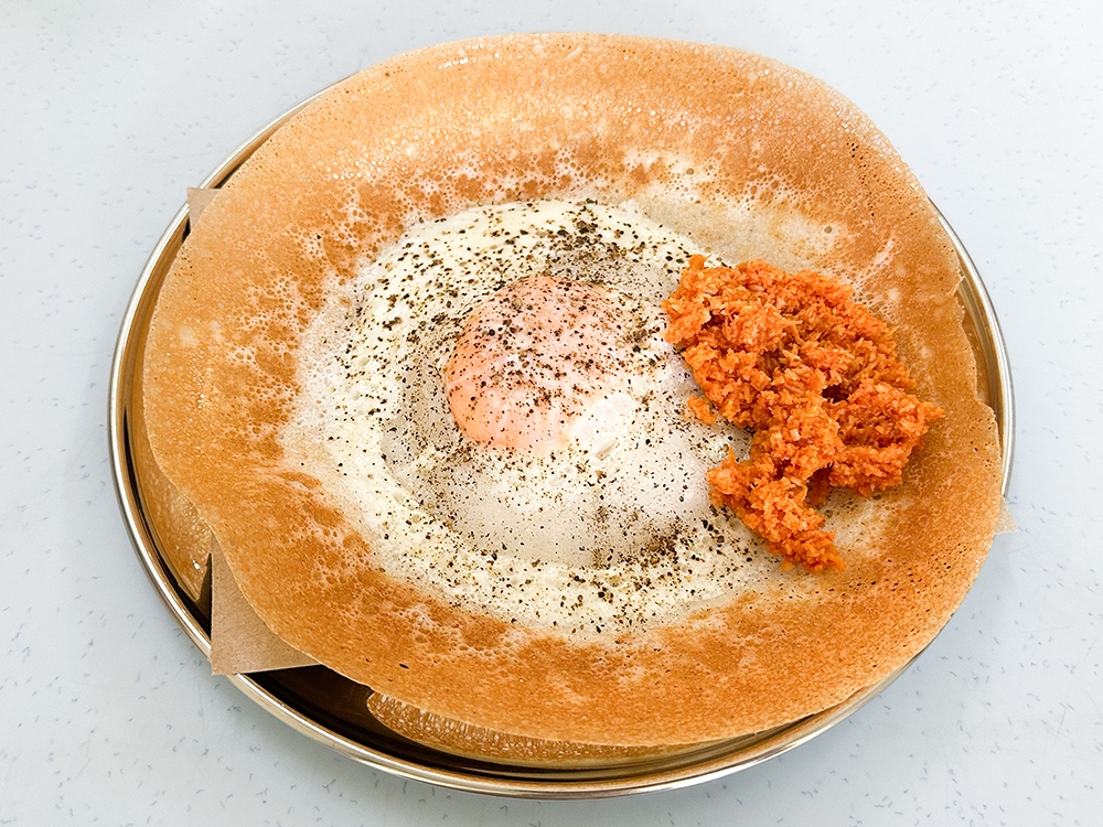 Here's the ultimate savoury treat; Egg Appam with a runny yolk is sprinkled with black pepper and served with a dollop of coconut 'sambal'