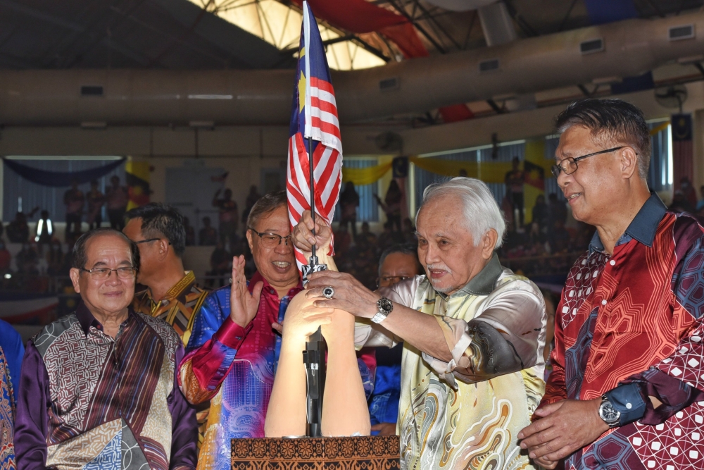 Taib (second, right) inserts the Jalur Gemilang flag into the hand sculpture to symbolically officiate the state-level National Day celebration in 2022 while Premier Datuk Patinggi Tan Sri Abang Johari Tun Openg (second, left), Uggah (left) and Sarawak Utility and Telecommunications Minister Datuk Seri Julaihi Narawi (right) look on. ― Penerangan pic via Borneo Post
