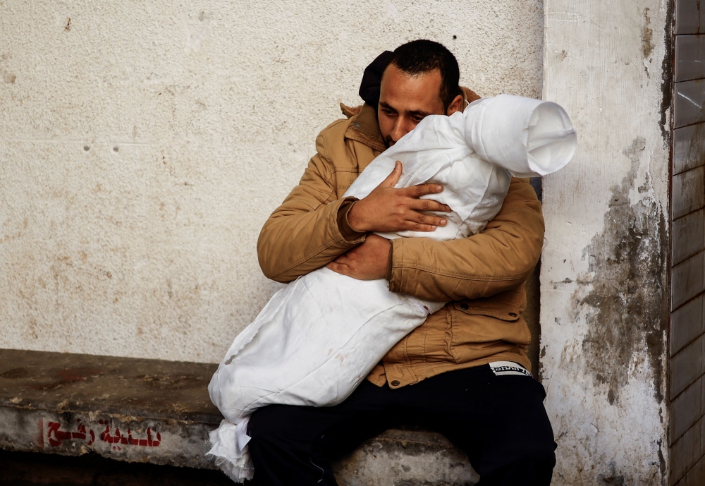 A Palestinian man carrying the body of his daughter who was killed in an Israeli strike at the Abu Yousef Al-Najjar hospital in Rafah. — Reuters pic