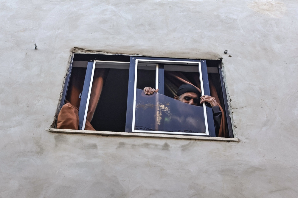 A Palestinian man stands by a broken window following an overnight Israeli raid in Jenin in the occupied West Bank on February 21, 2024. — AFP pic