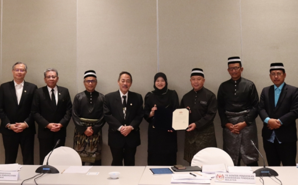 Datu Dr Azhar Ahmad (third right) shows the documents together with Fadhlina Sidek (fourth right). Also seen are Datuk Indera Nik Nasarudin Zawawi (2nd right), Datuk Seri Roland Sagah Wee Inn (fourth left), Datuk Dr Annuar Rapaee (3rd left) and other officers from MEITD and MoE. — Borneo Post pic 