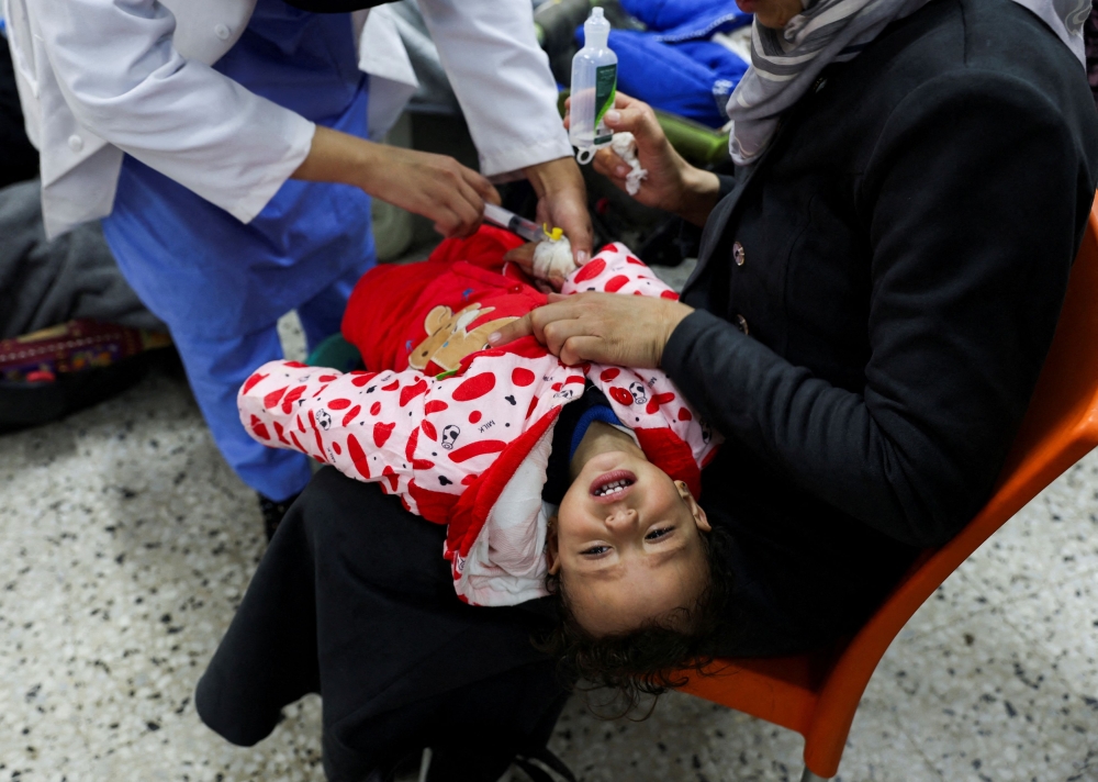 A Palestinian child is treated by a doctor at a health centre in Rafah. — Reuters pic