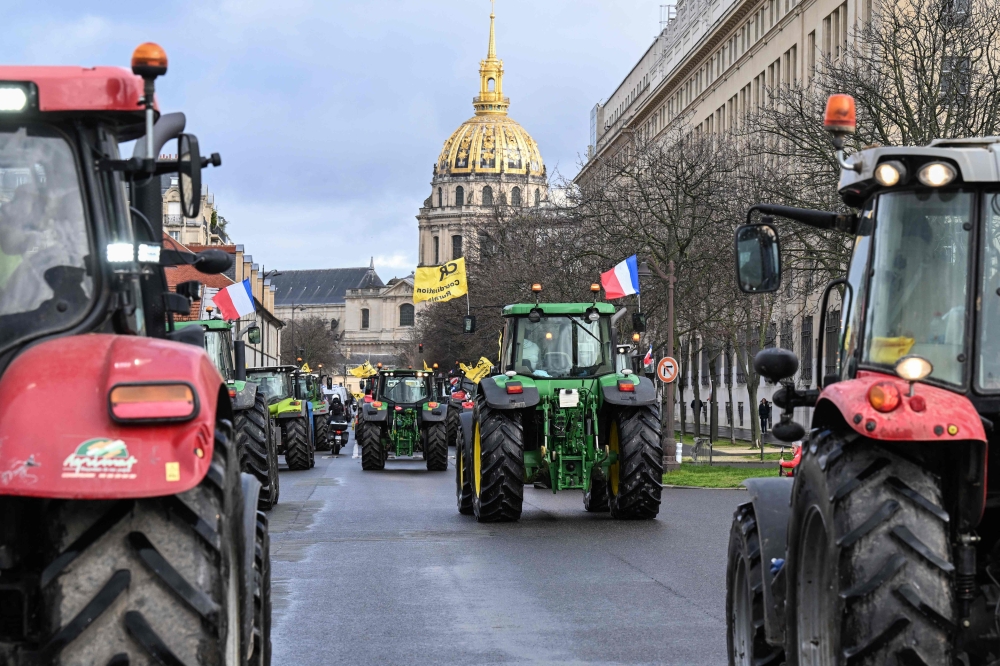 French farmers drive tractors during a demonstration of the Coordination Rurale agricultural union, ahead of the opening of the 60th International Agriculture Fair (Salon de l'Agriculture), with a view of the Dome of the Hotel des Invalides in the background, western Paris February 23, 2024. — AFP pic
