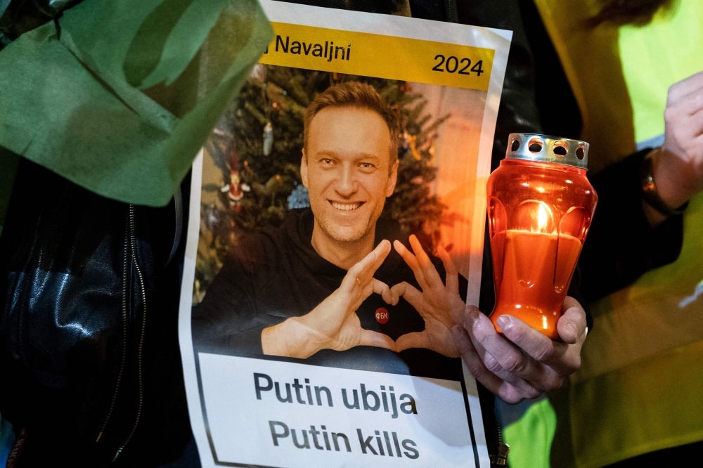 A person holds a candle and a portrait of late Russian opposition leader Alexei Navalny, who died in a Russian Arctic prison, as people gather at a makeshift memorial in downtown Zagreb on February 23, 2024. — AFP pic